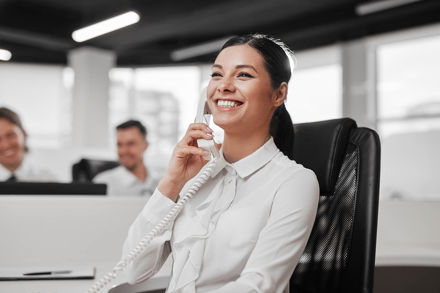 Delighted secretary speaking on telephone with client